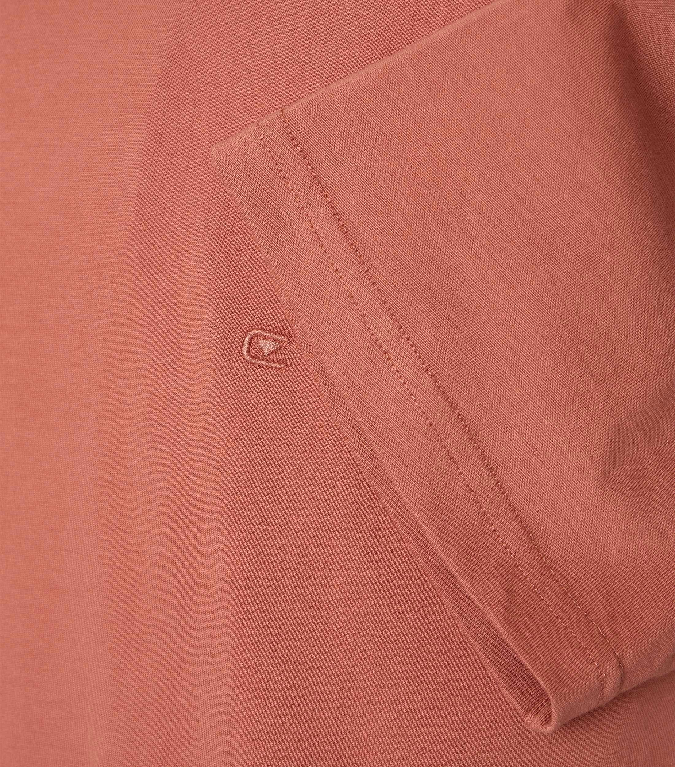 Das Model trägt ein TShirt im uni Muster in der Farbe Hellorange