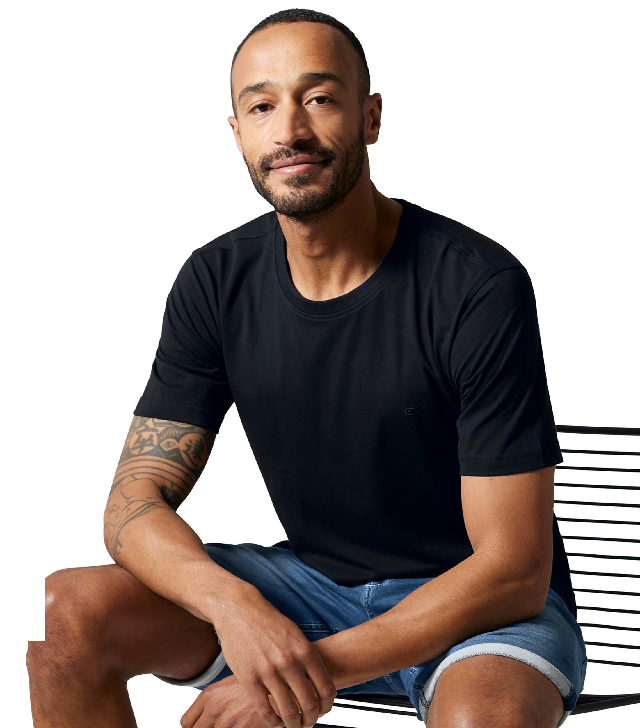 Das Model trägt ein TShirt im uni Muster in der Farbe Schwarz