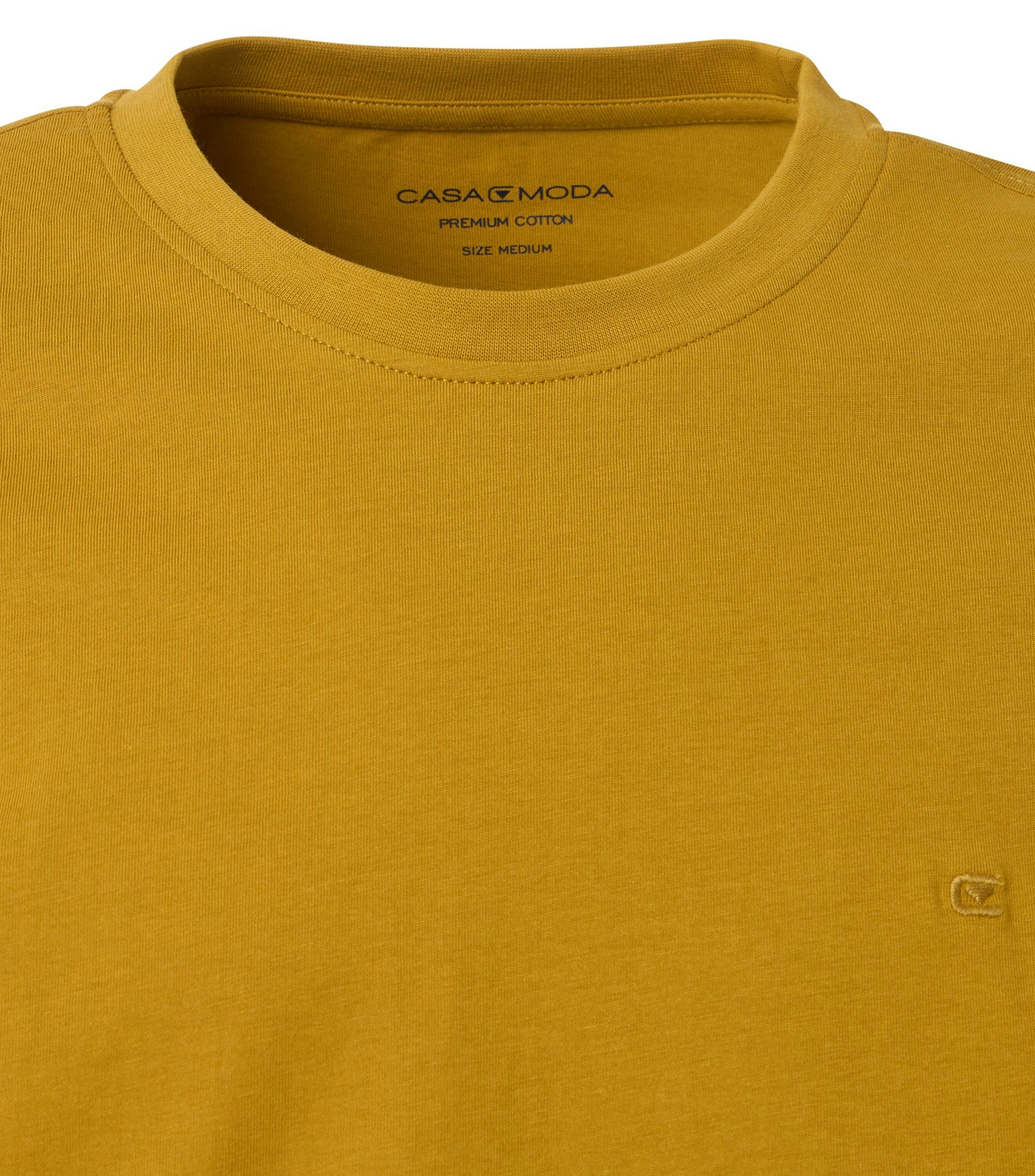 Das Model trägt ein TShirt im uni Muster in der Farbe Honiggelb