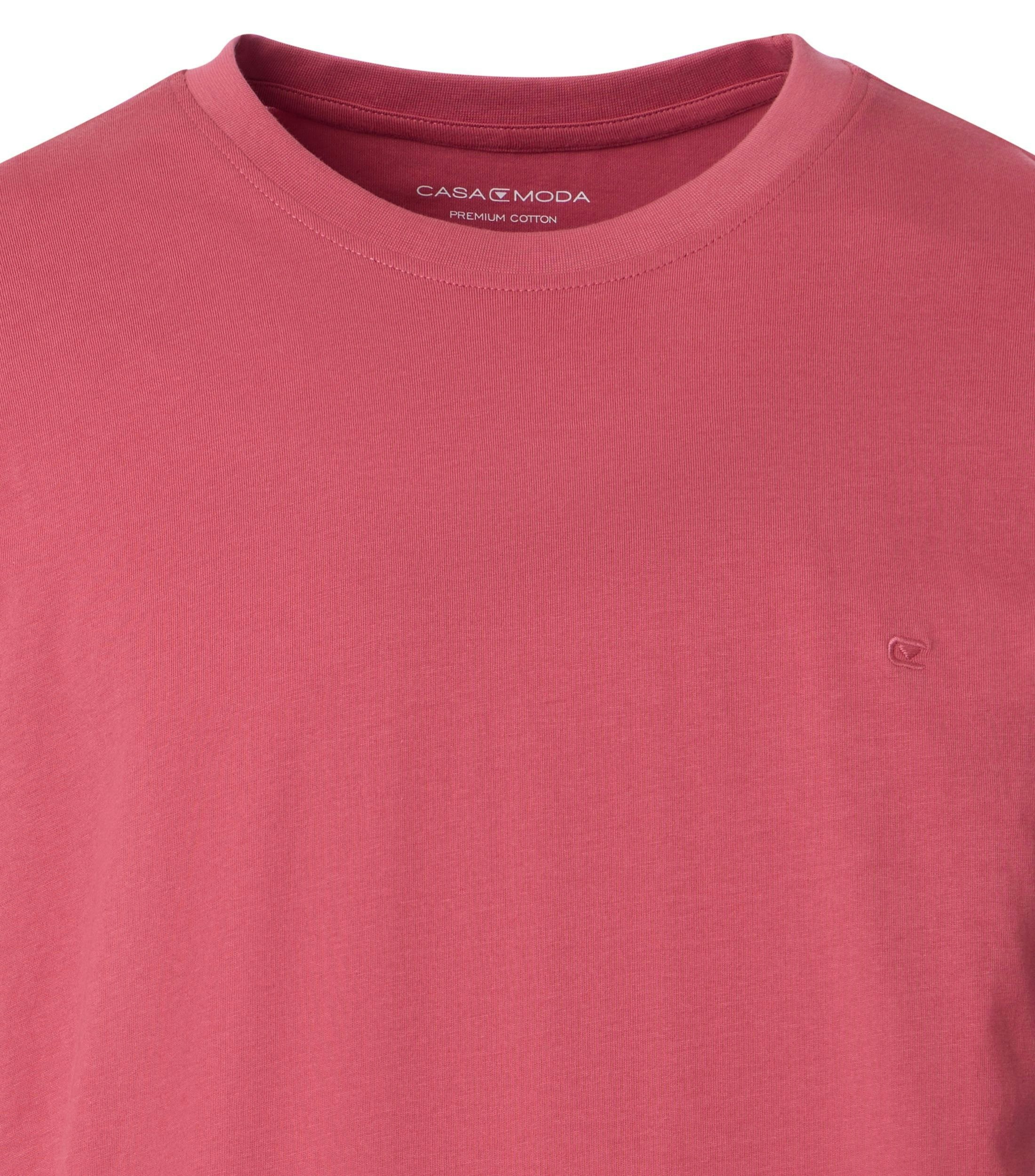 Das Model trägt ein TShirt im uni Muster in der Farbe Hellrot