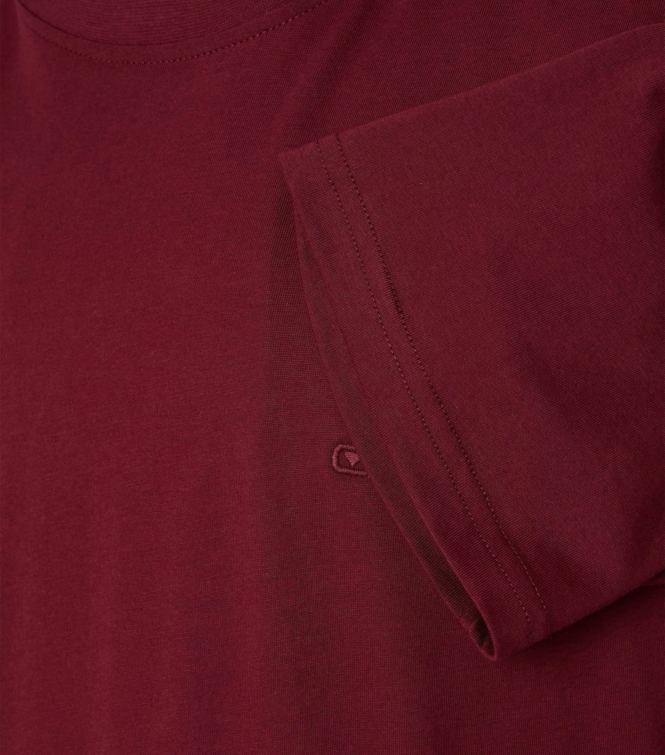 Das Model trägt ein TShirt im uni Muster in der Farbe Bordeauxrot