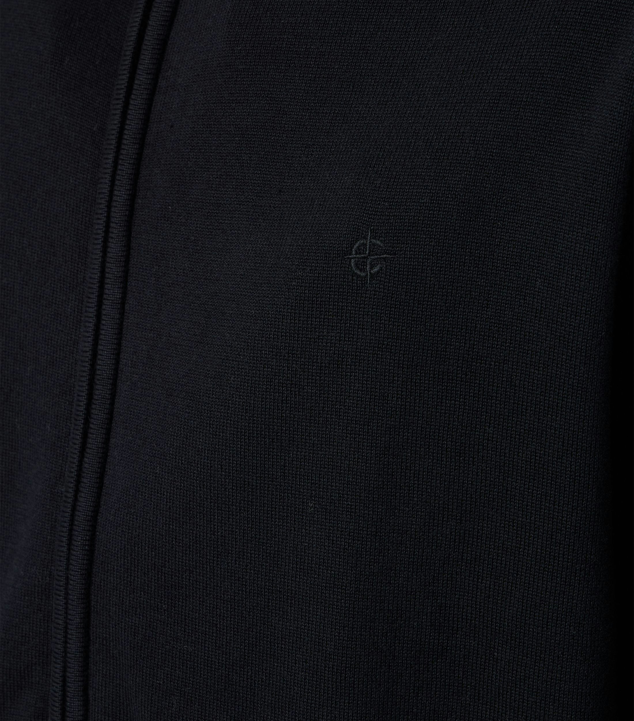 Das Model trägt eine Strickjacke im uni Muster in der Farbe Schwarz