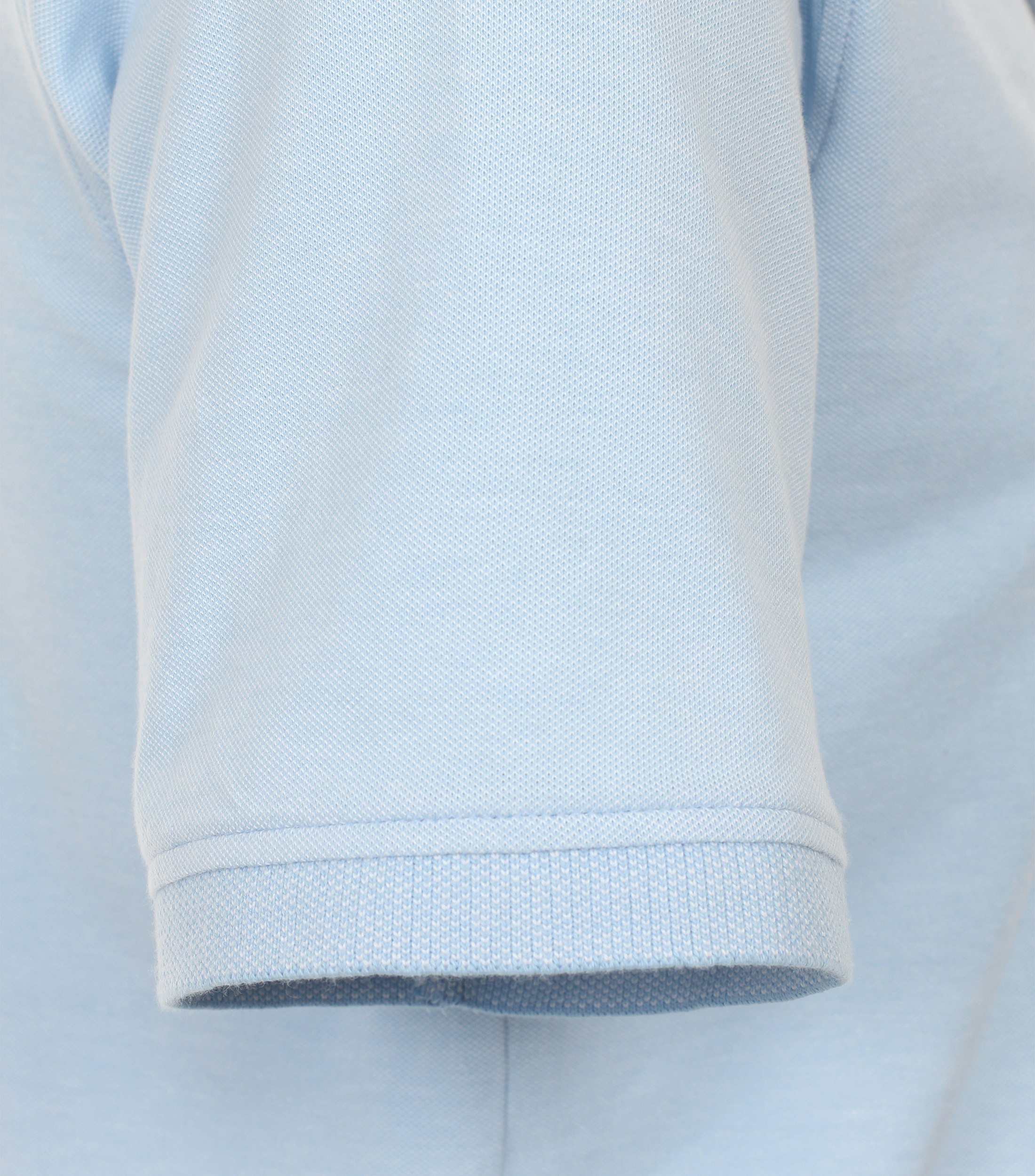 Das Model trägt ein PoloShirt im uni Muster in der Farbe Hellblau