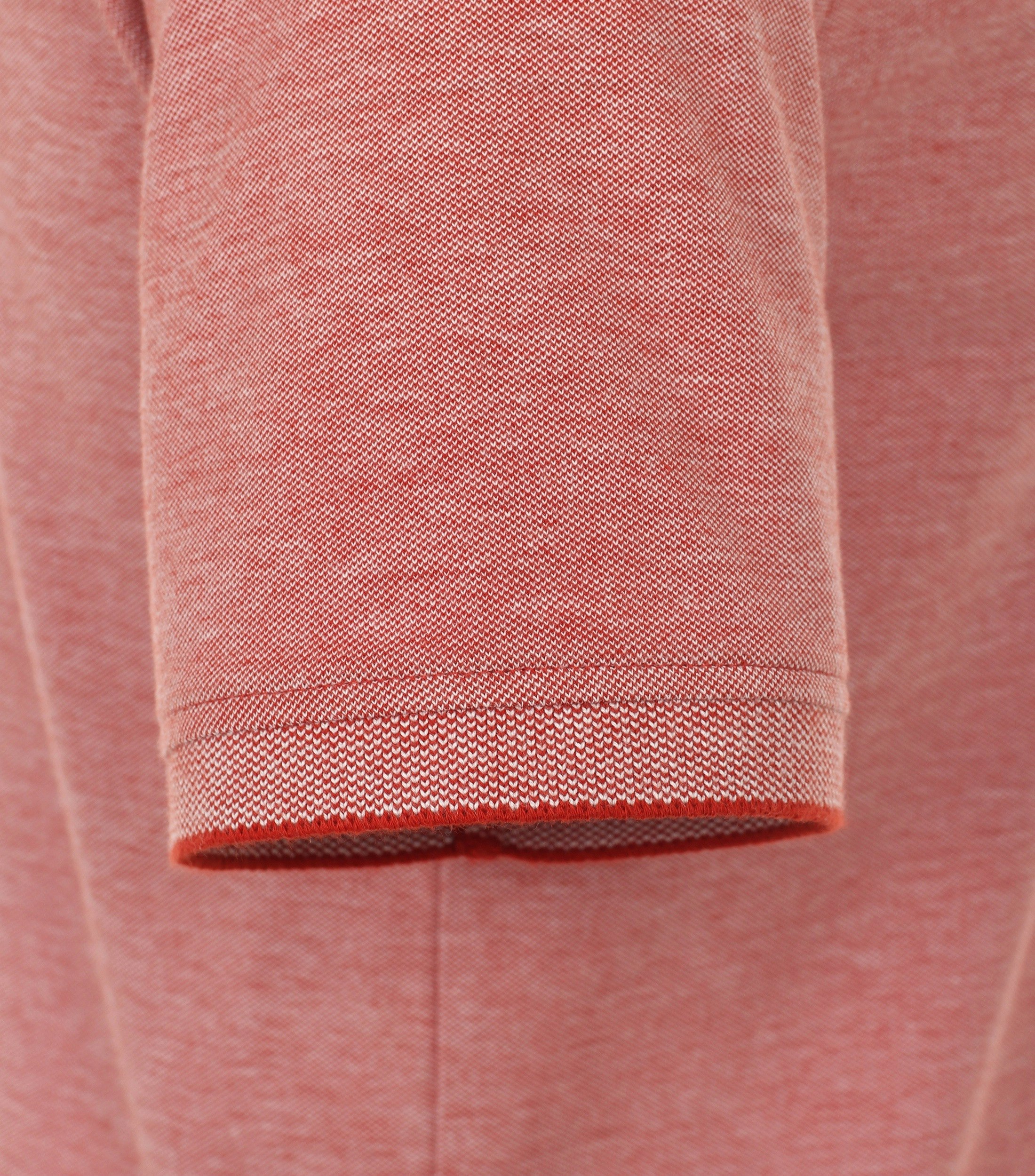 Das Model trägt ein PoloShirt im uni Muster in der Farbe Dunkelorange