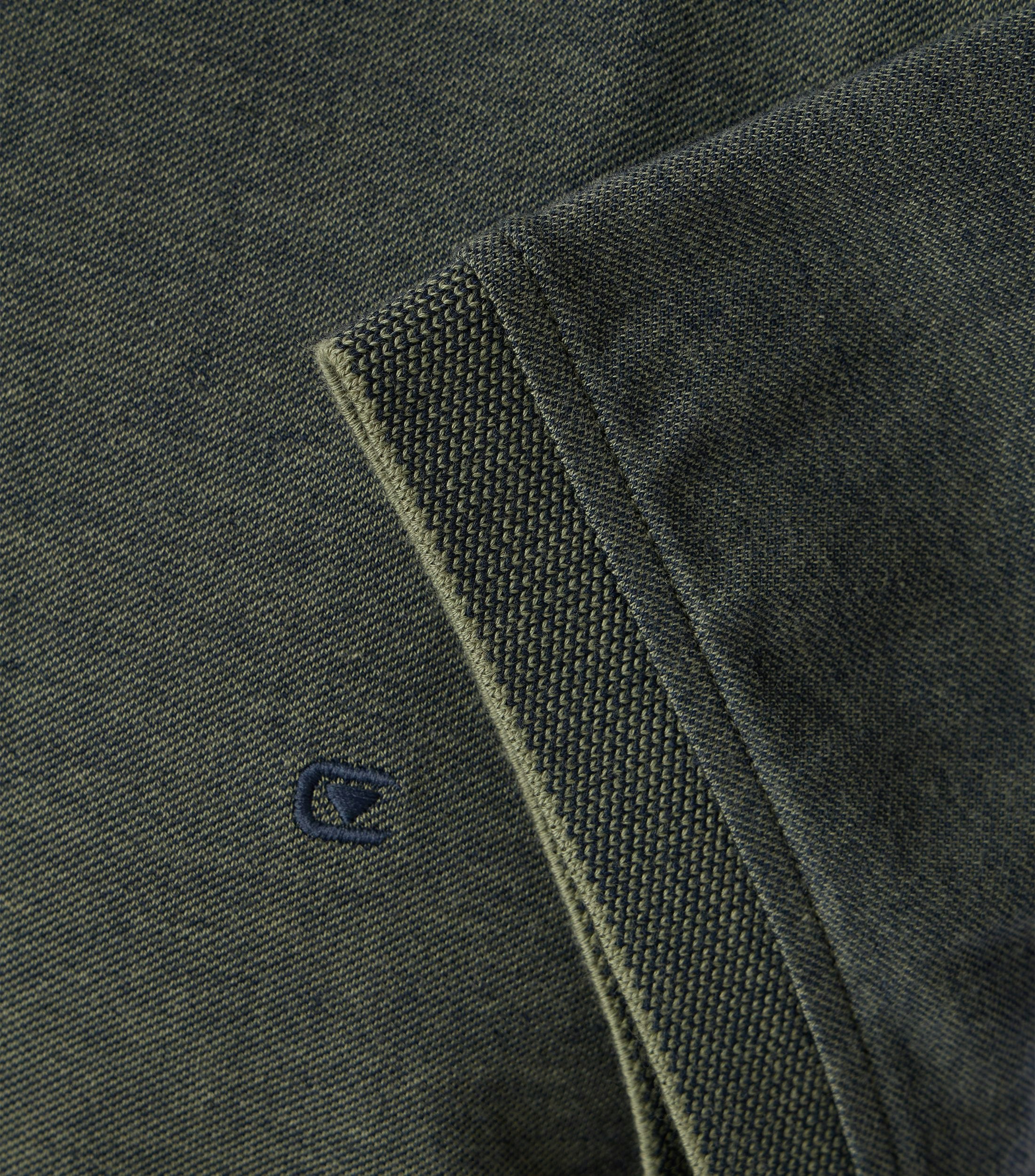 Das Model trägt ein PoloShirt im uni Muster in der Farbe Dunkelgrün