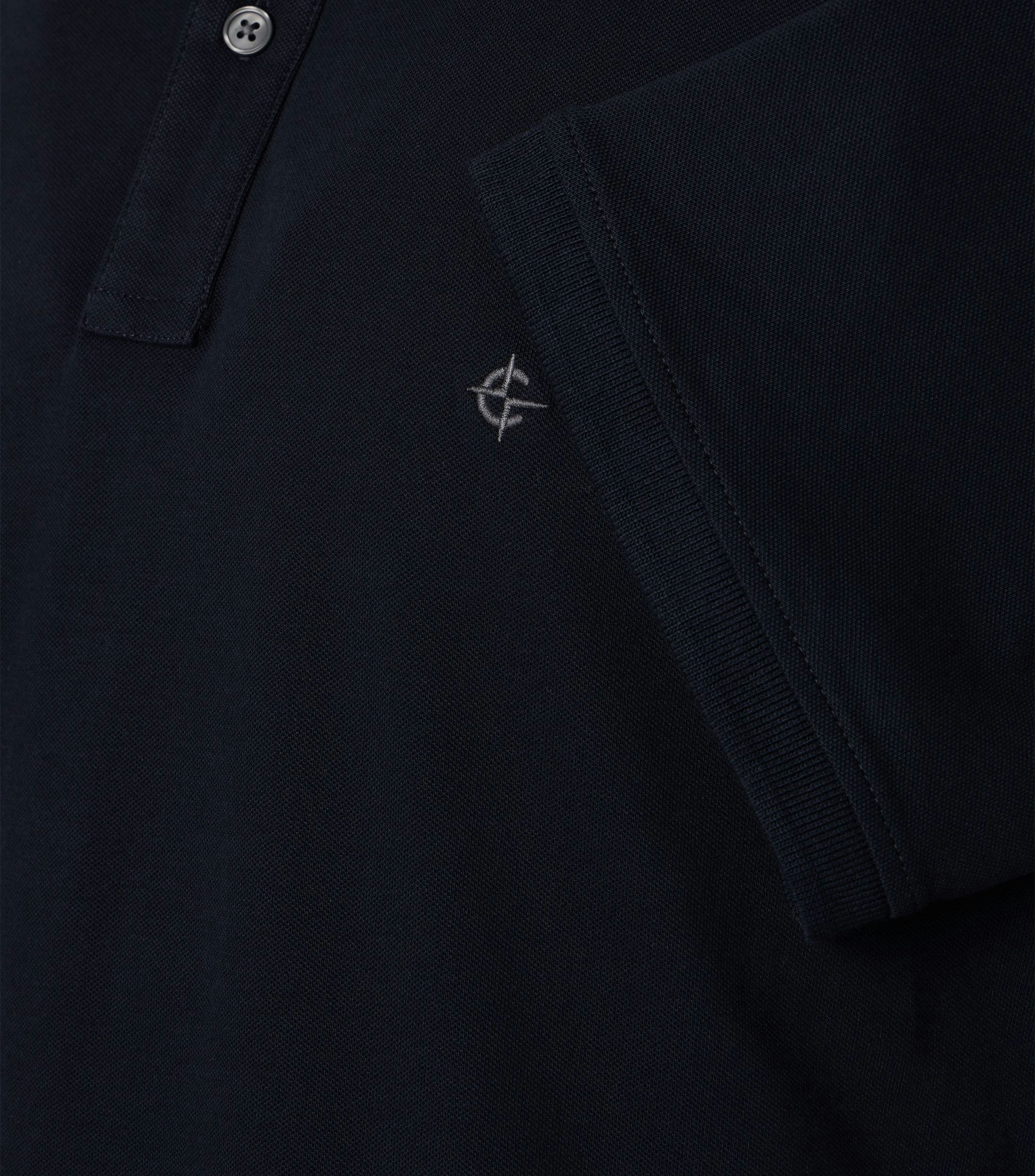 Das Model trägt ein PoloShirt im uni Muster in der Farbe Dunkelblau