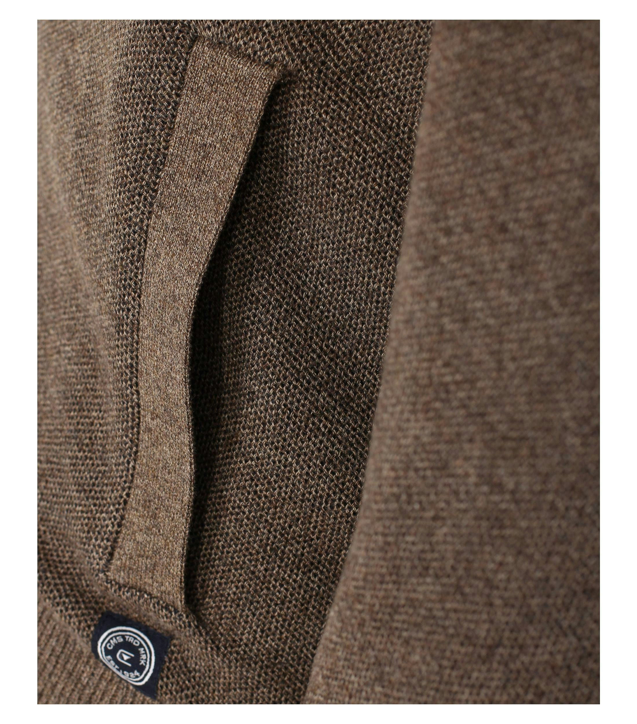 Das Model trägt eine Strickjacke im uni Muster in der Farbe Beige