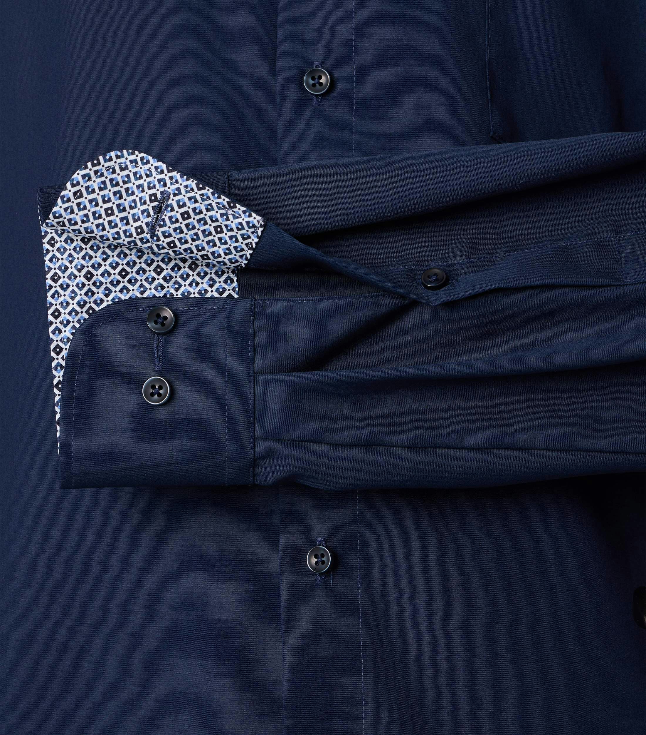 Das Model trägt ein Businesshemd im uni Muster in der Farbe mittleres Dunkelblau